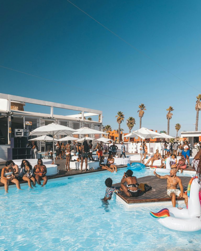 Participants autour d’une piscine pour Afro Nation, festival afrobeat à Portimão au Portugal, sous les palmiers.