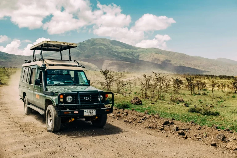 Véhicule tout-terrain équipé pour les safaris circulant sur une piste de terre au milieu de paysages
