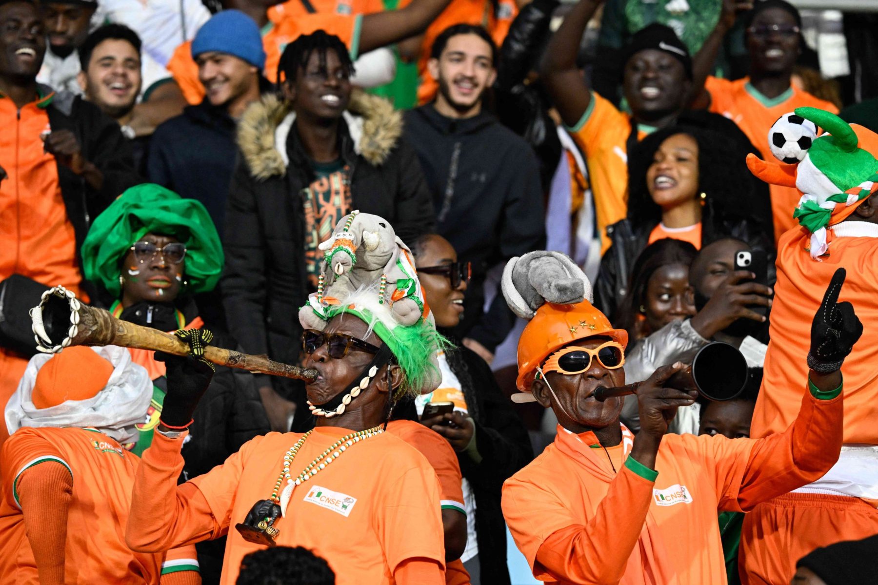 supporters ivoiriens dans un stade football qui mettent l'ambiance avec des vouvouzela et des cirnes