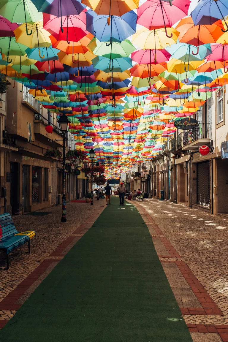 Rue d’Águeda au Portugal décorée de centaines de parapluies multicolores suspendus au-dessus des passants.